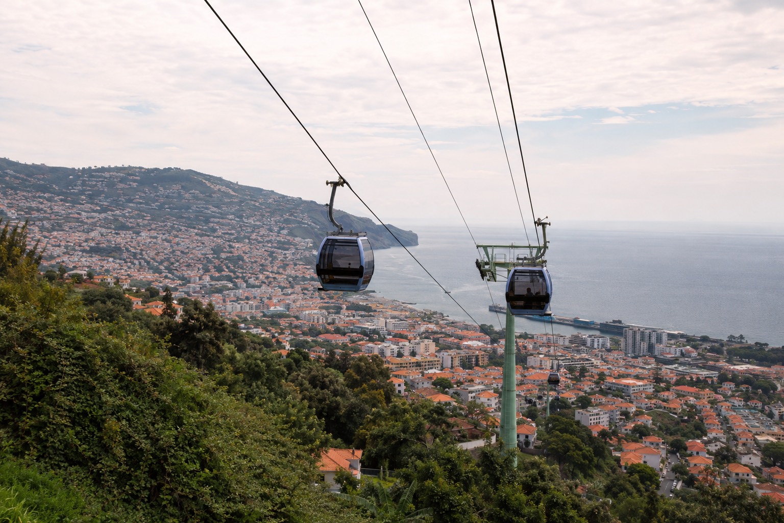 Linbanans gondoler på väg upp mot Monte med Funchal och havet nedanför